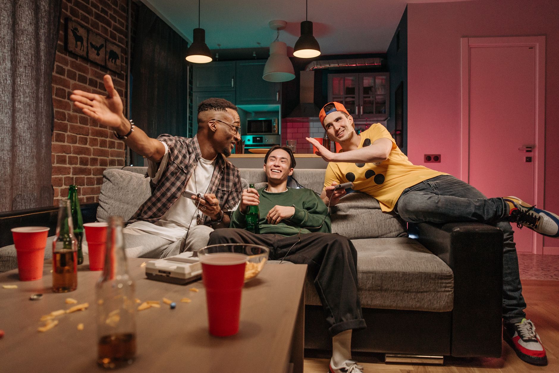 Three friends laughing around a table with games and drinks