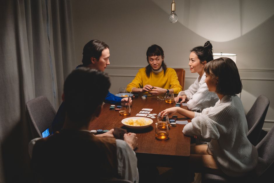 Friends around a table with cards, drinks and snacks