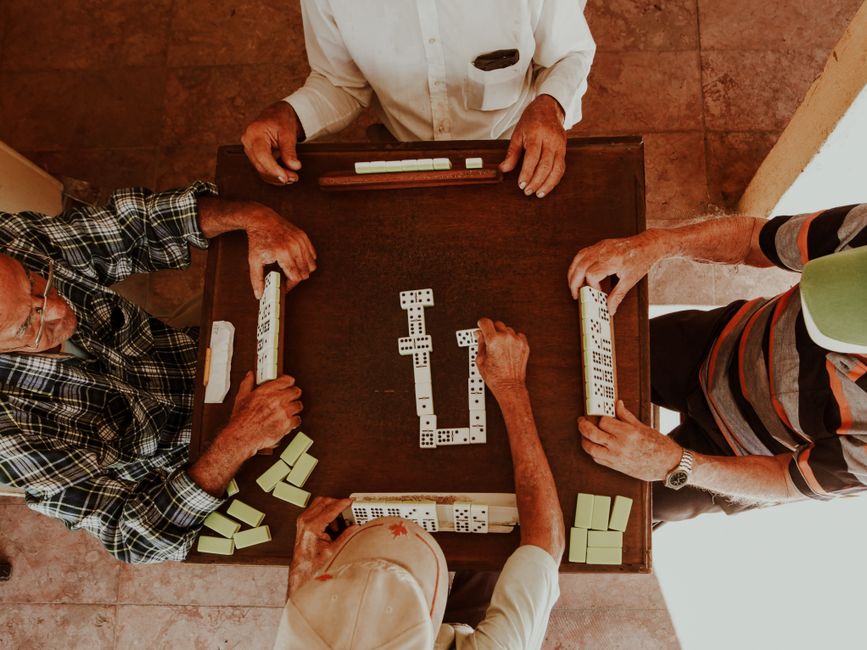 Older adults playing dominoes at an indoor table
